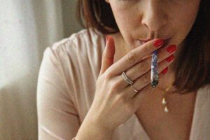 Woman holding a joint in lips with hand