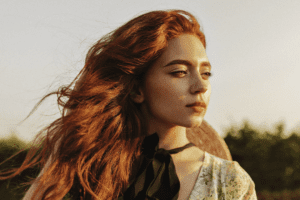 A red headed woman stares off into the distance.