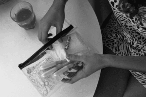 A woman pulls a CBD tampon from a feminine hygiene bag while sitting at a table.