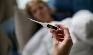 Woman taking the temperature with a thermometer