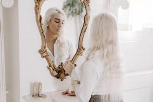 A woman looks into a mirror while smoking a Delta-8 vape from Botany Farms.