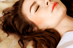 Smiling woman on bed, eyes closed in bliss