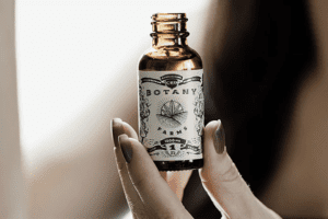 A hand holds up a bottle of CBD oil used to make CBD oral spray