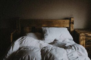 A photo of a messy wooden bed in a dimly lit room.
